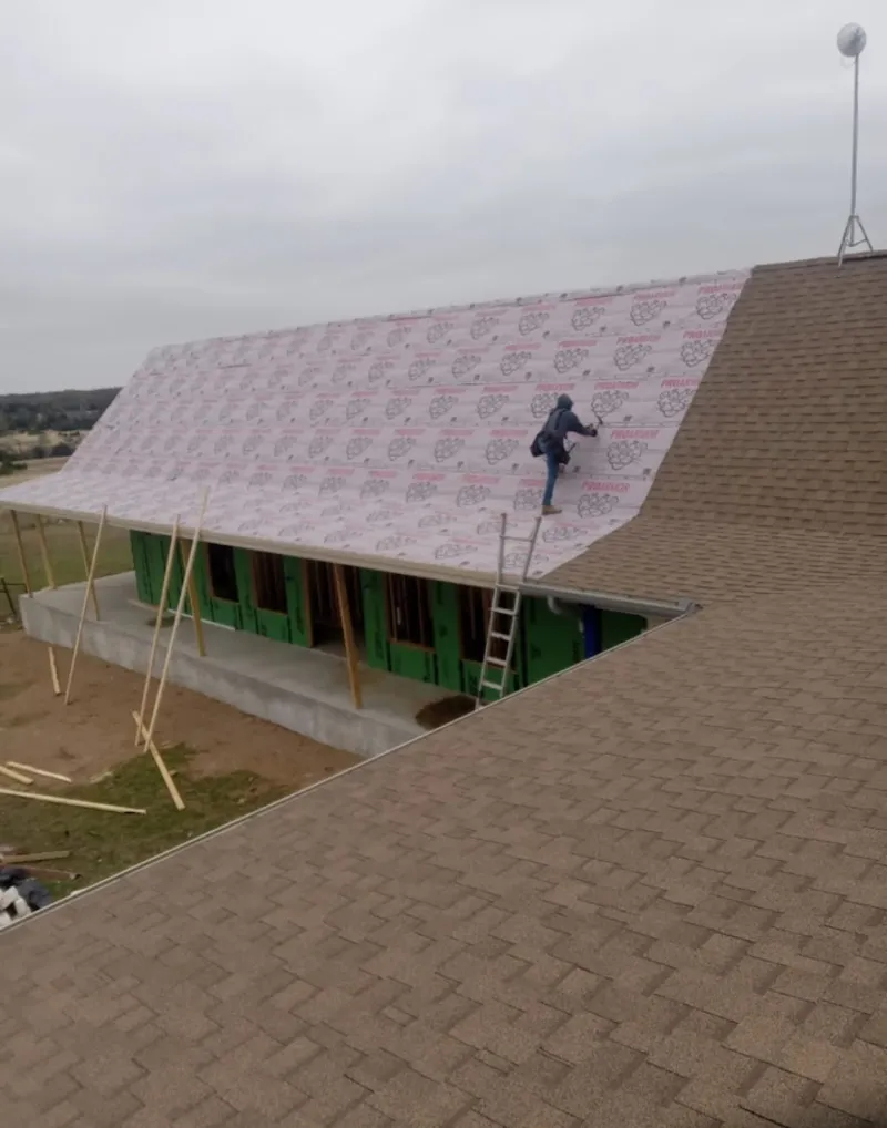 Worker preparing underlayment for a metal roof installation in Hobbs